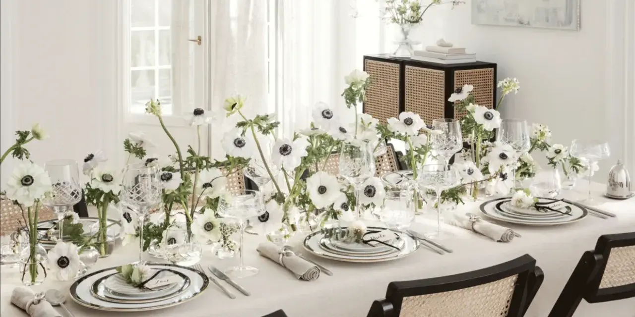 Ett elegant dukat bord med vita anemoneblommor och kristallglas. En diskret detalj är sugrör guld som ger en lyxig touch.