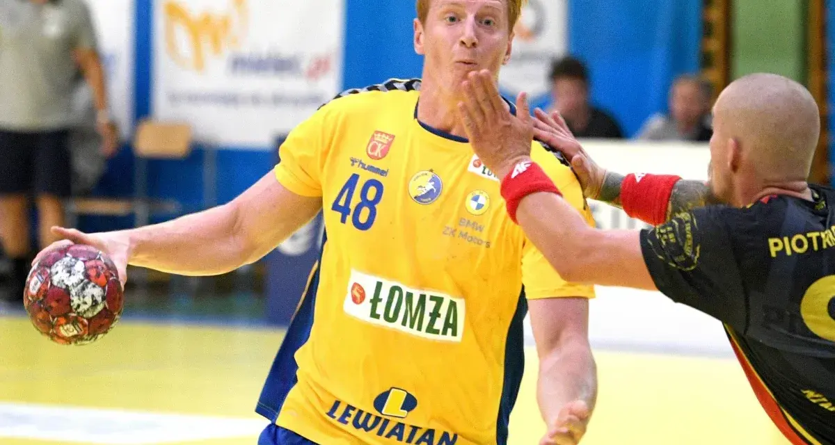 Tomasz Gębala w żółtej koszulce z numerem 48 łapie piłkę do ręcznej, broniąc się przed przeciwnikiem.