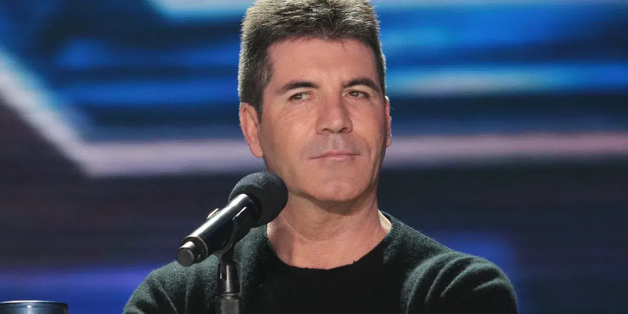 Simon Cowell, znany z surowych ocen, siedzi przy mikrofonie. Plotki o tym, że Simon Cowell nie żyje, są fałszywe.