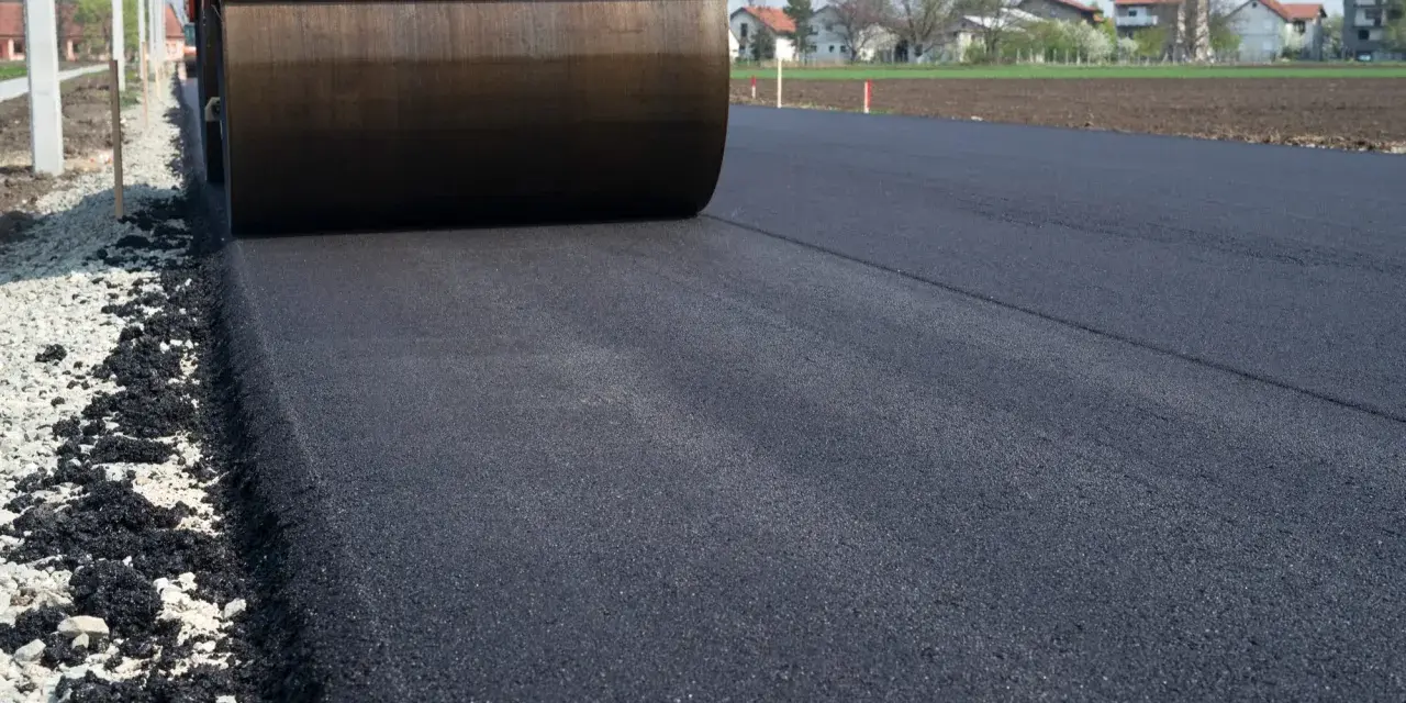 Walec drogowy ugniata świeży asfalt. Zastanawiasz się, ile kosztuje 1m2 asfaltu?