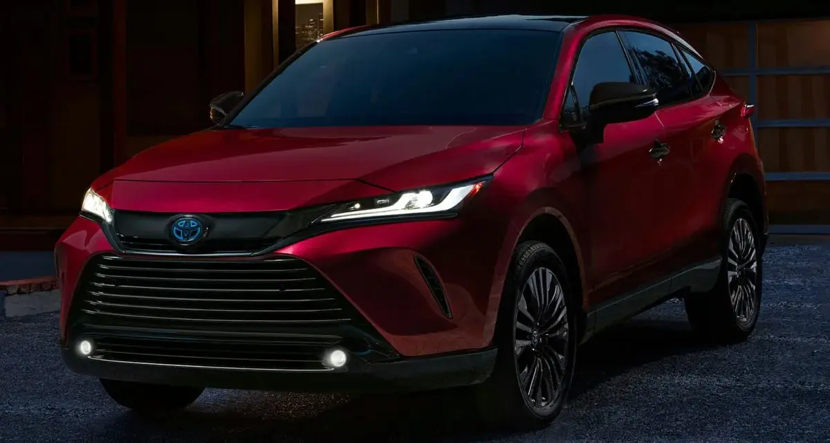 Elegancka, czerwona Toyota Venza z nowoczesnymi światłami LED stoi przed domem o zmierzchu.