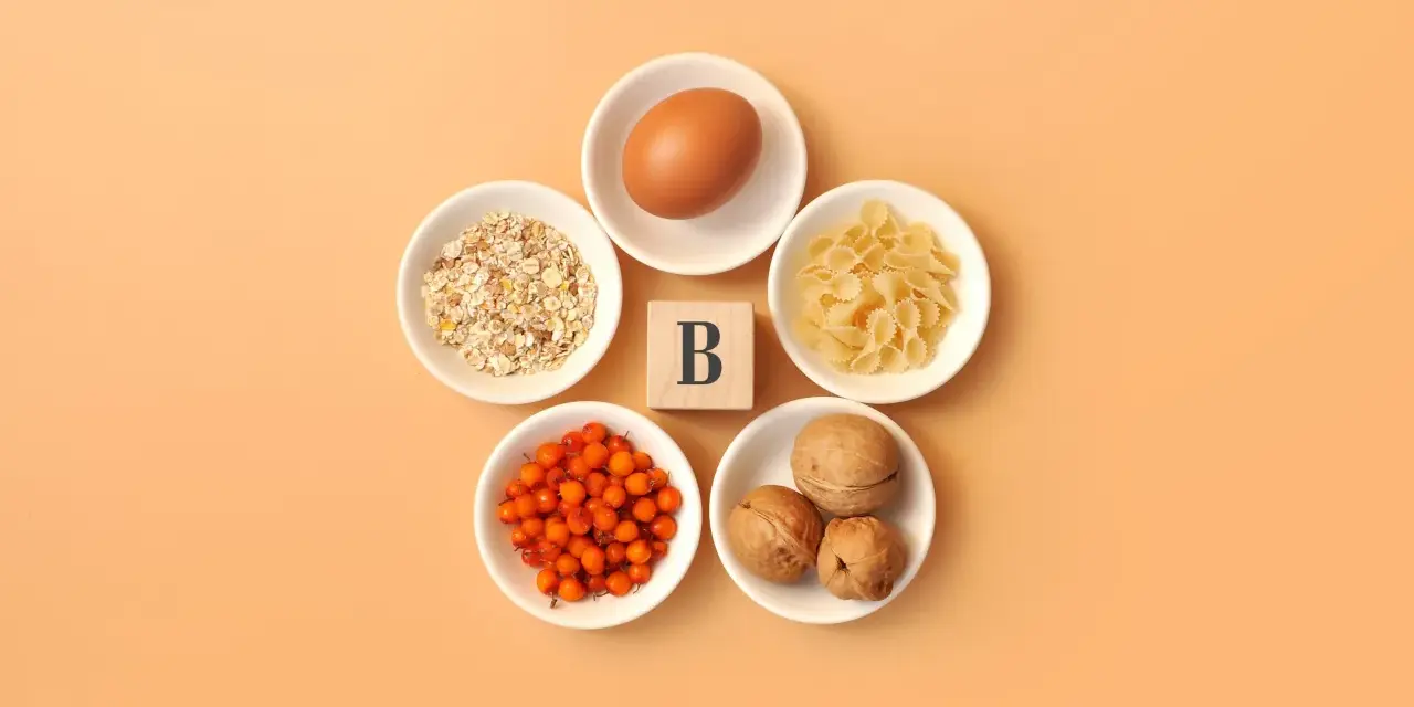 En ägg, havregryn, pasta, havtorn och valnötter arrangerade runt en träkub med bokstaven B, som symboliserar alla b-vitaminer.