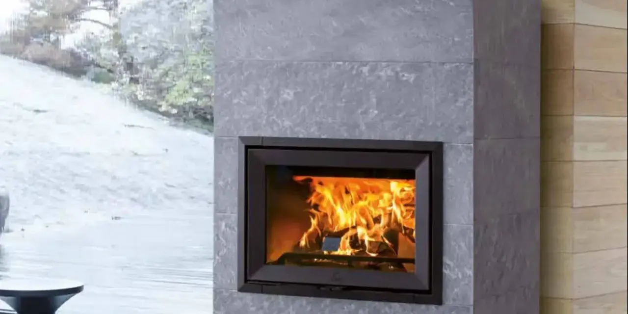Chimenea moderna de piedra gris con fuego crepitante. Es hora de insertarleña para mantener el calor.