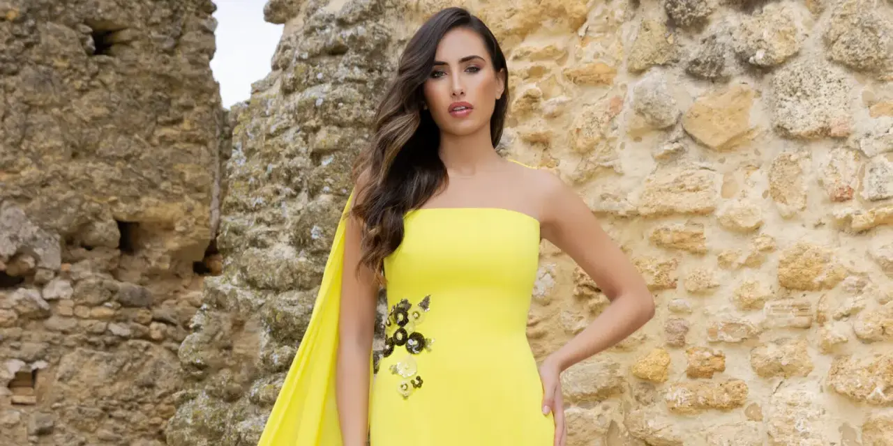 Mujer con vestido amarillo sin tirantes, con detalles florales y capa. Explora los diversos tipos de cuellos de vestidos.
