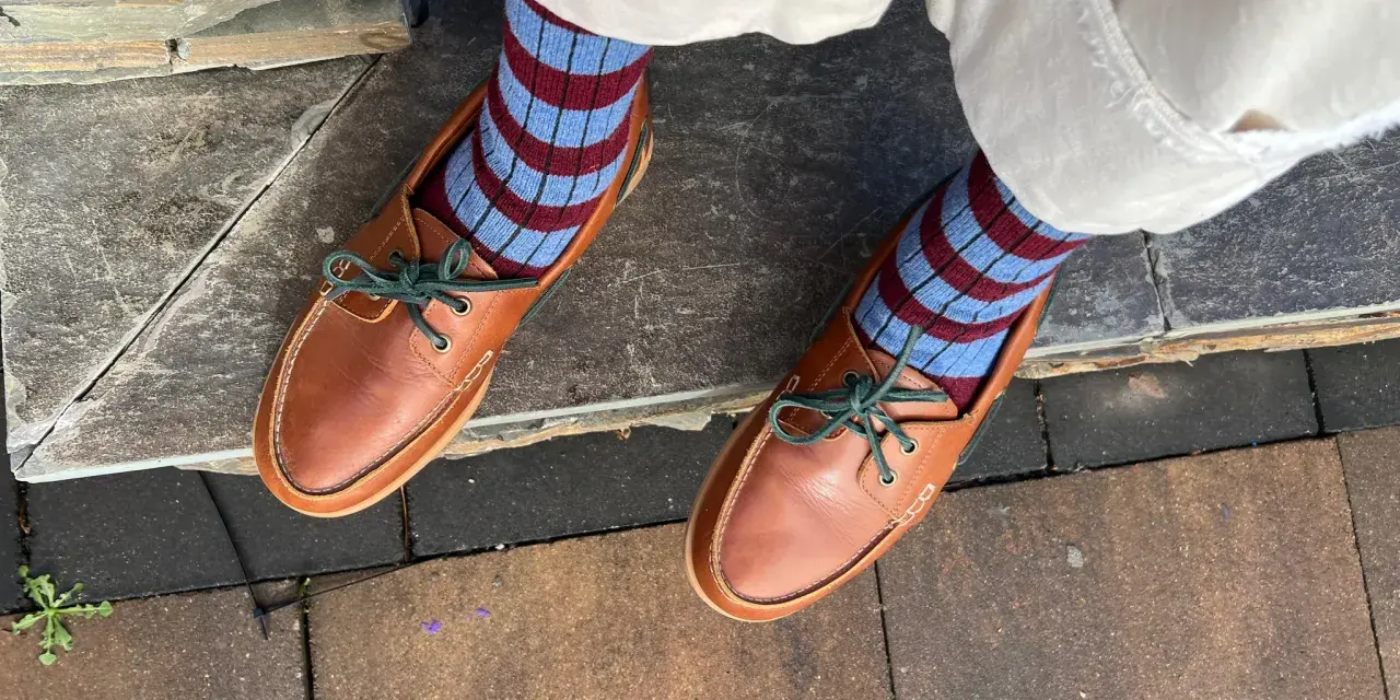 Pies con calcetines a rayas azul y burdeos y mocasines de cuero marrón. Un ejemplo de cómo combinar color teja ropa con estilo.