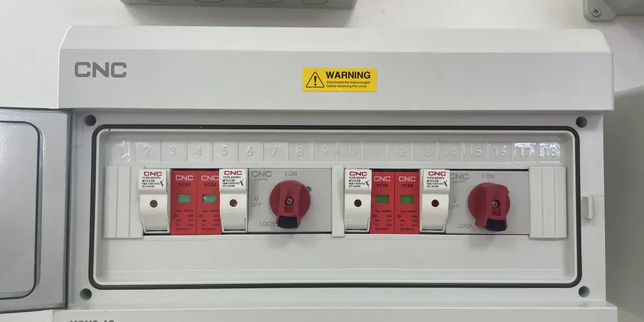 Biała skrzynka elektryczna z czerwonymi przełącznikami i numerowanymi slotami.