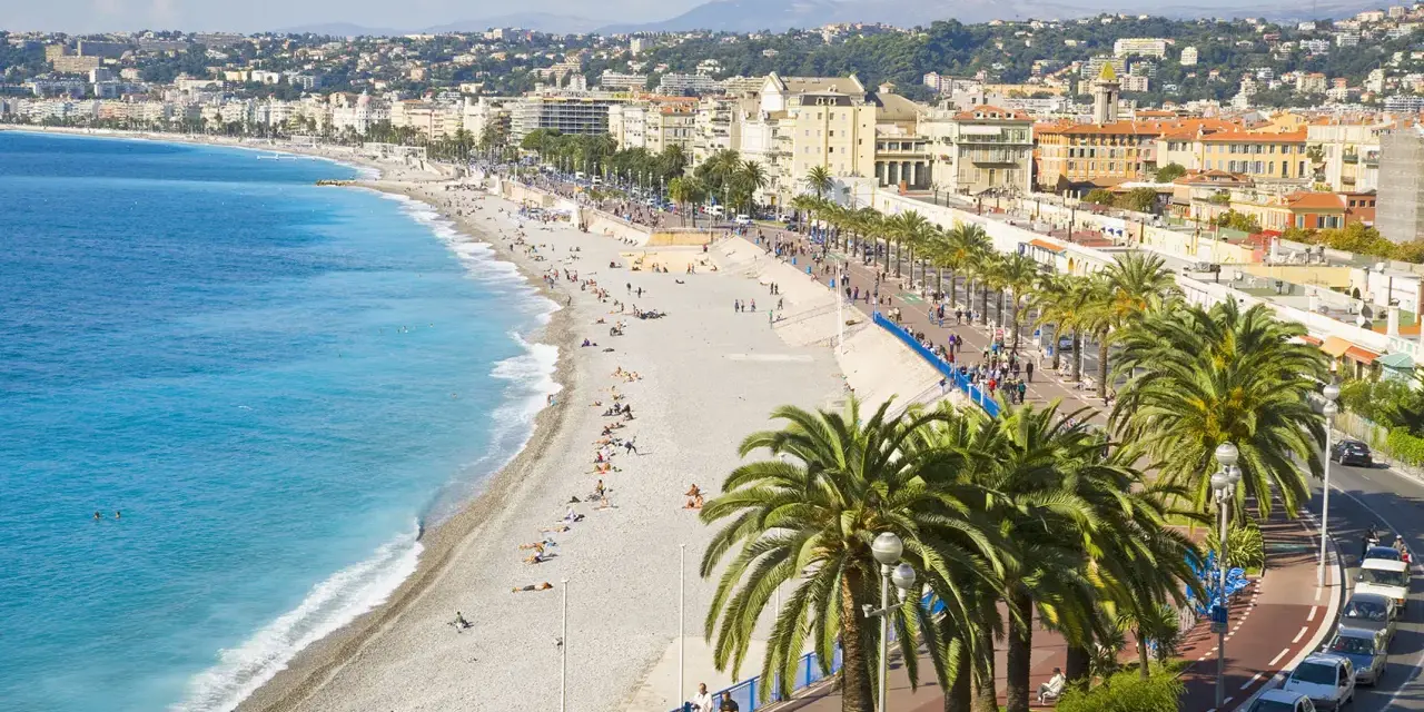 Spiaggia di Nizza, un luogo ideale per pensare a come trovare lavoro all'estero, con palme e mare azzurro.