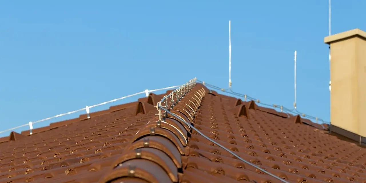 Nowy dach z brązowej dachówki, na którym zamontowano nowoczesną instalację odgromową, chroniącą przed burzami.