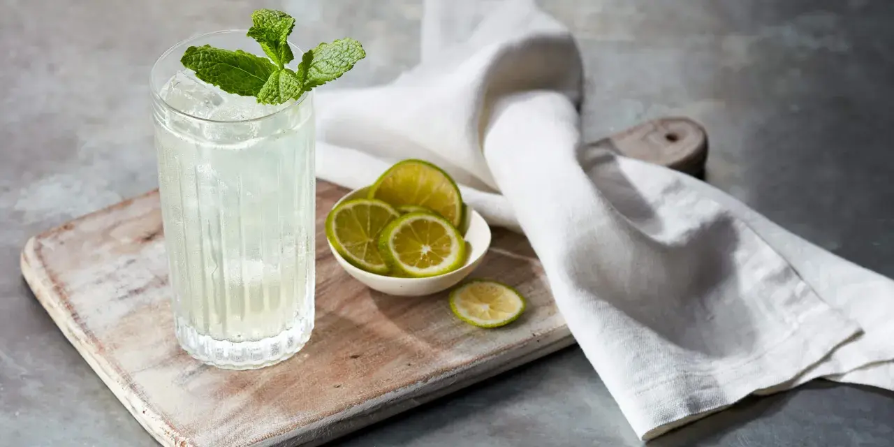 Orzeźwiający mojito z ginem, udekorowany miętą i podany z plasterkami limonki na drewnianej desce.
