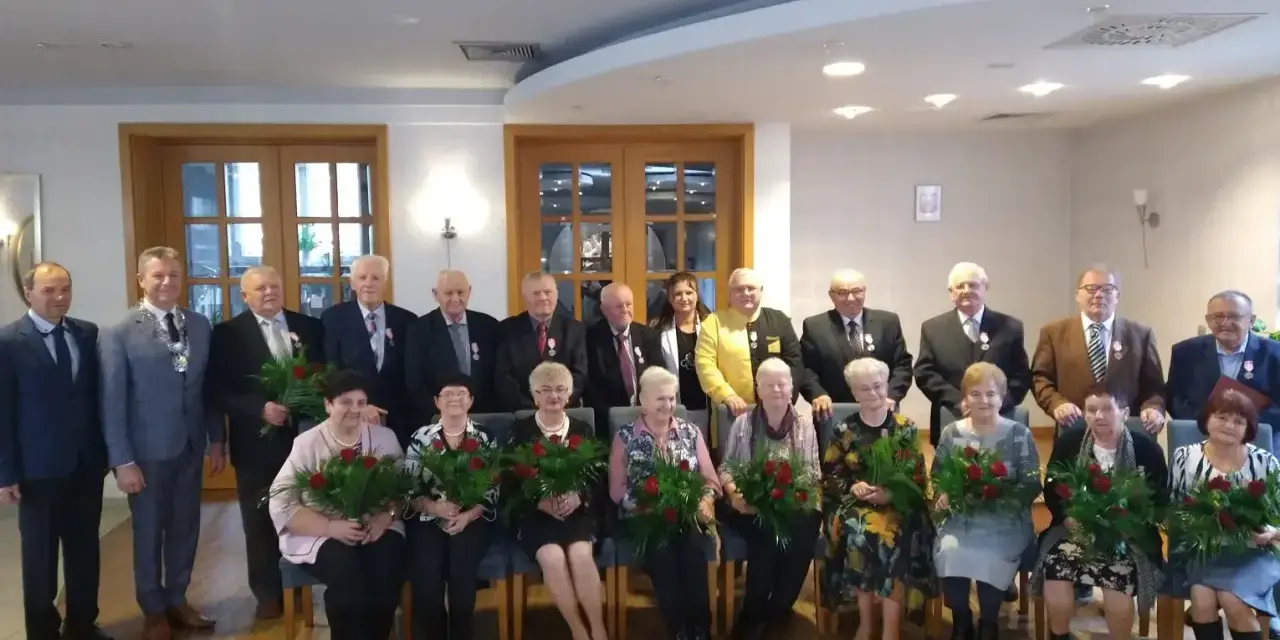 Grupa osób świętuje 50 rocznicę ślubu. Wszyscy otrzymują róże i medale.