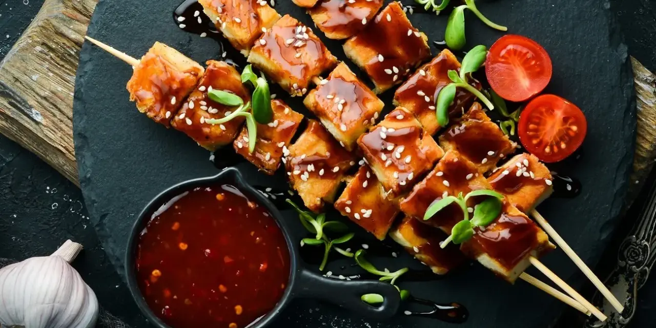 Hähnchenspieße mit glänzender Teriyaki-Sauce, Sesam und Kirschtomaten. Ein köstliches teriyaki sauce rezept zum Nachmachen.