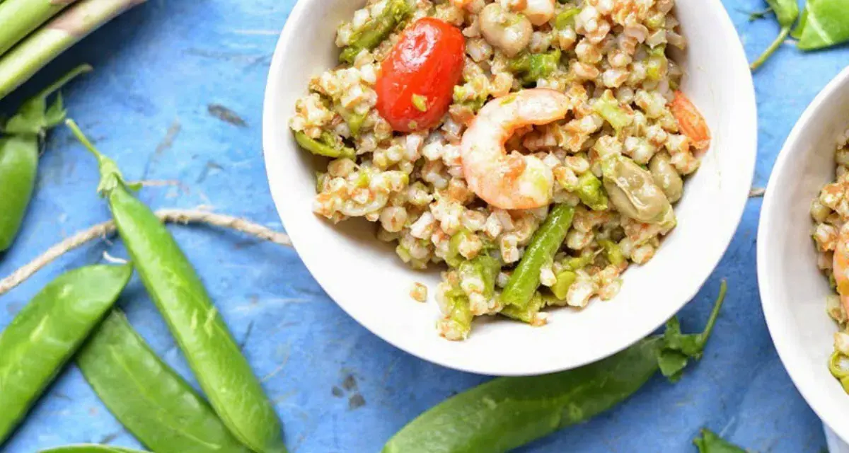 Deliziosa insalata di cereali con gamberetti, pomodorini, asparagi e fave. Un piatto fresco e nutriente.