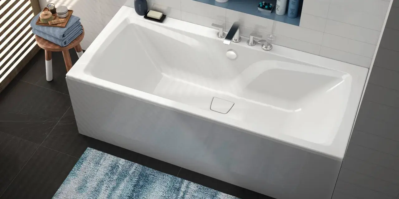 Baignoire blanche moderne, d'une largeur baignoire standard, avec robinetterie chromée et étagère murale.