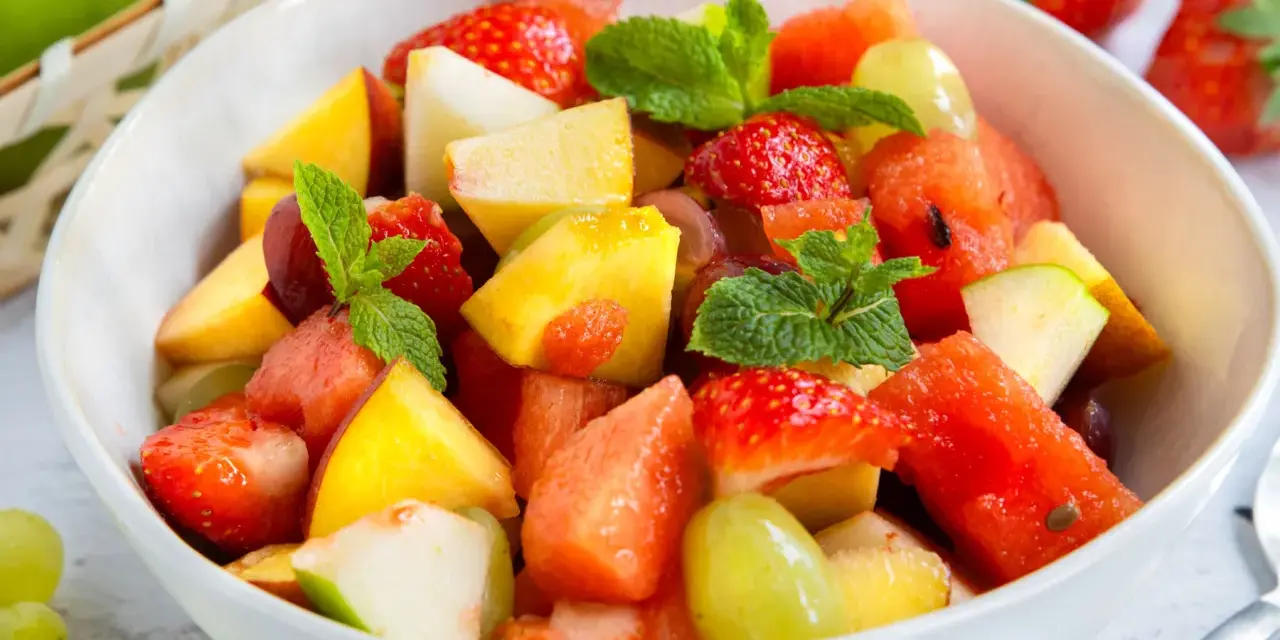 Ein bunter Obstsalat mit Erdbeeren, Melone, Pfirsich und Trauben – ein einfaches obstsalat rezept für heiße Tage.
