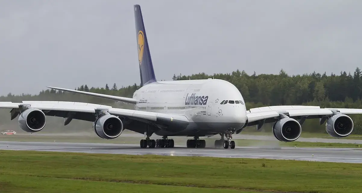 Lufthansa A380, największy samolot pasażerski, kołuje po mokrym pasie startowym.