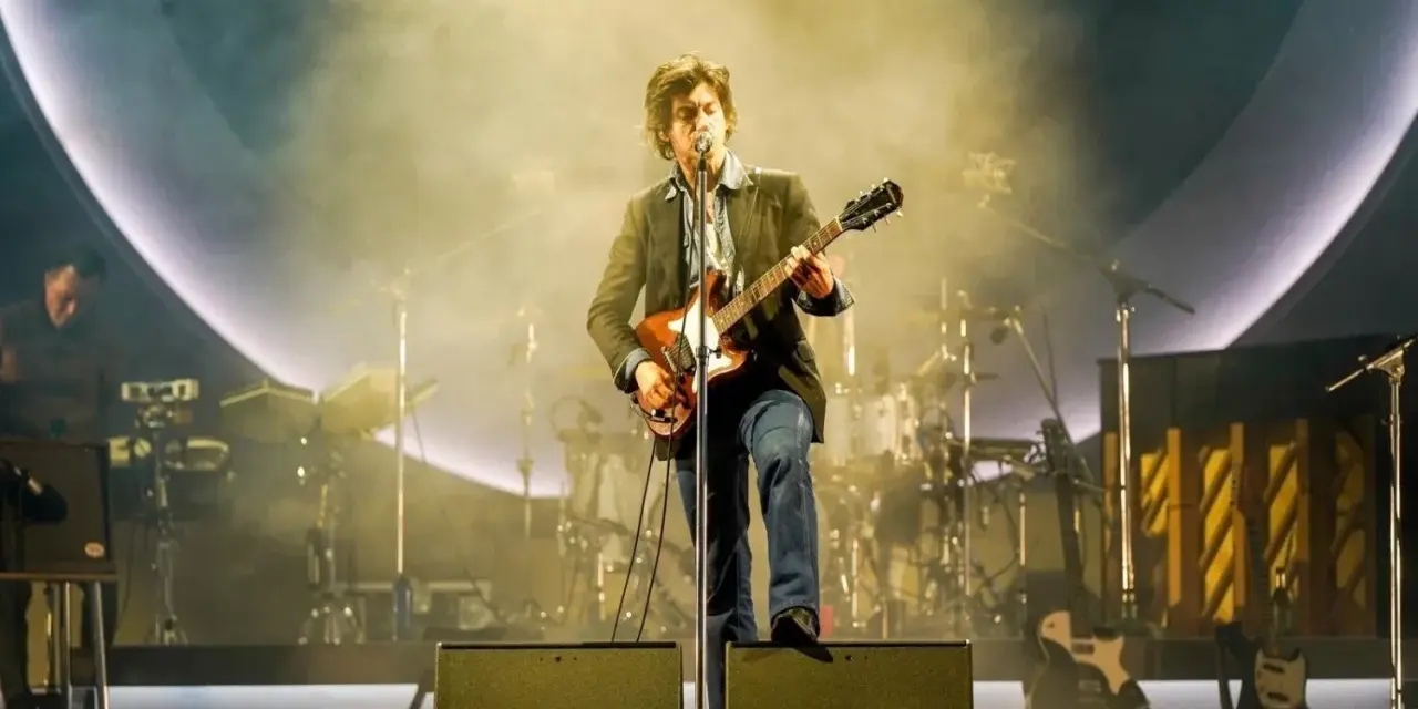 Alex Turner z Arctic Monkeys Polska na scenie, grając na gitarze w otoczeniu dymu i świateł.
