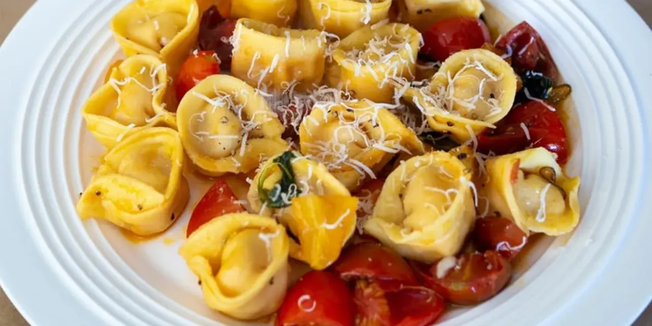 Pyszne tortellini z pomidorkami i parmezanem na białym talerzu. Idealne danie, czy ravioli czy tortellini?