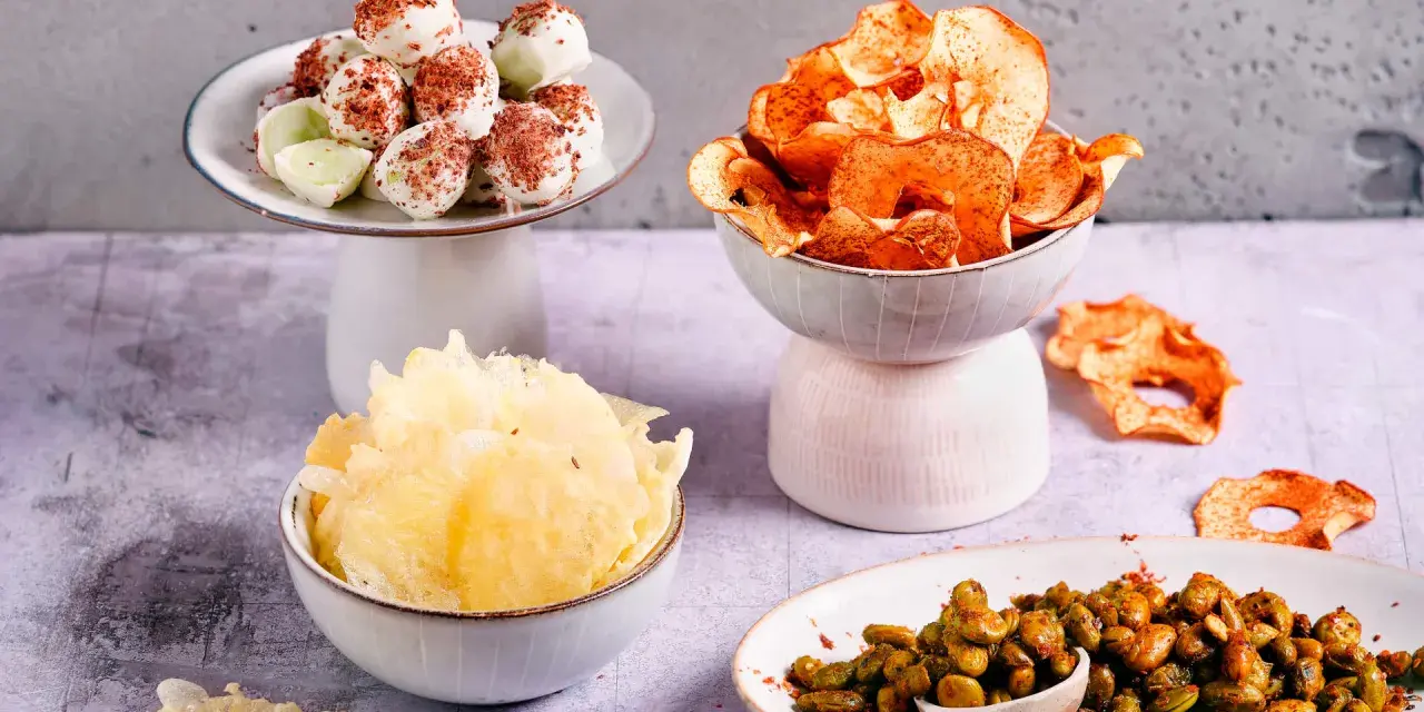 Leckere filmabend snacks: weiße Schoko-Bällchen, Apfelchips, knusprige Cracker und gewürzte Edamame.