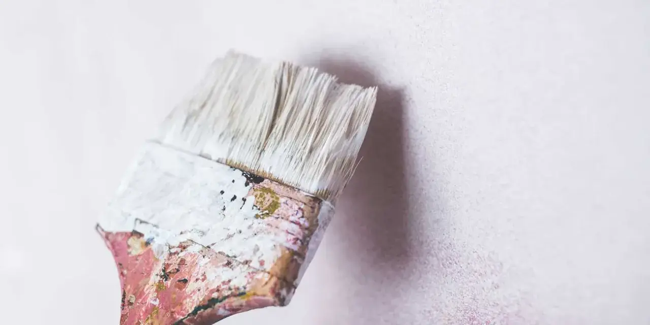 Pincel con restos de masilla para pared interior, listo para renovar.