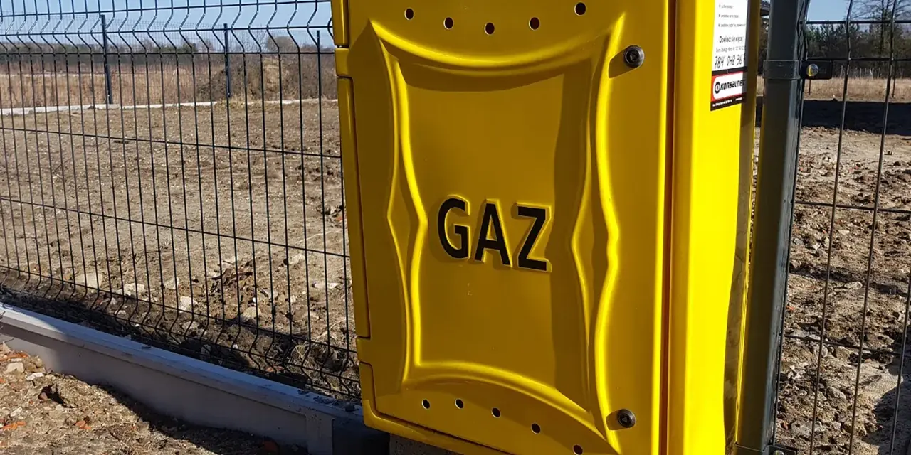 Żółta skrzynka gazowa z napisem "GAZ" przy ogrodzeniu. Zastanawiasz się, ile kosztuje przyłącze gazu?