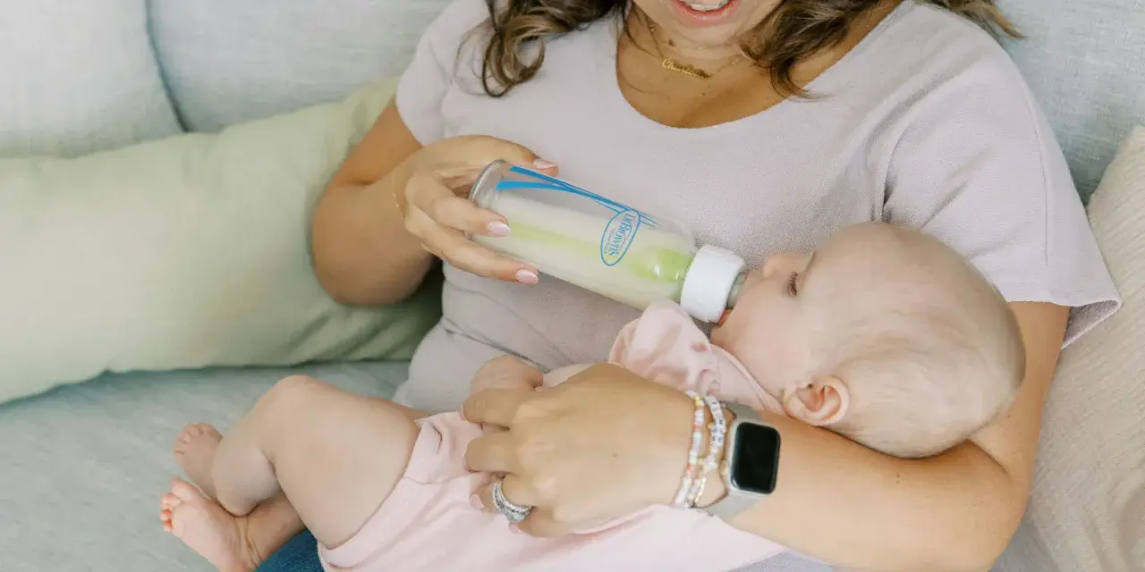 Kiedy zmienic przeplyw smoczka? Mama karmi dziecko butelką, obserwując, czy maluch nie ma problemów z jedzeniem.