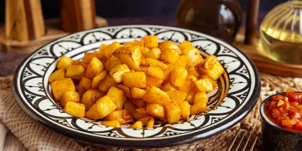 Knusprige patatas bravas in einer marokkanisch inspirierten Schale, daneben eine Schale mit scharfer Tomatensauce.
