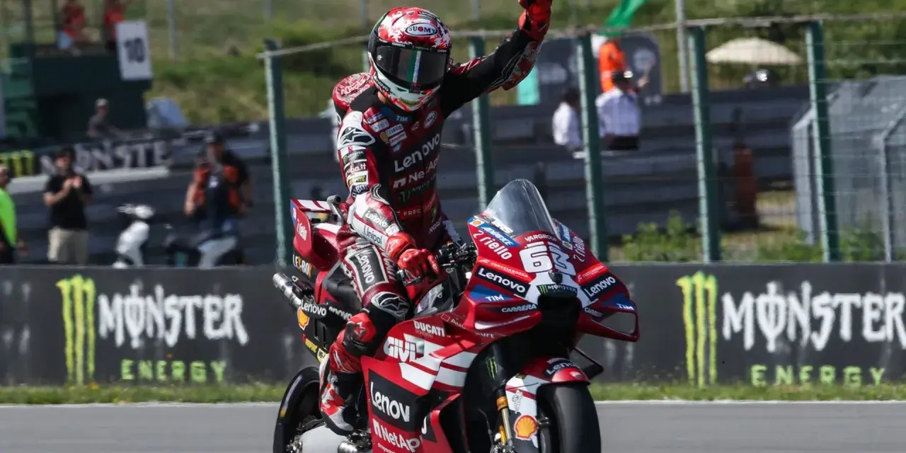 Piloto de MotoGP celebra victoria en su moto Ducati roja. Aunque no se especifica cuanto mide Marc Márquez, su presencia en la pista es imponente.