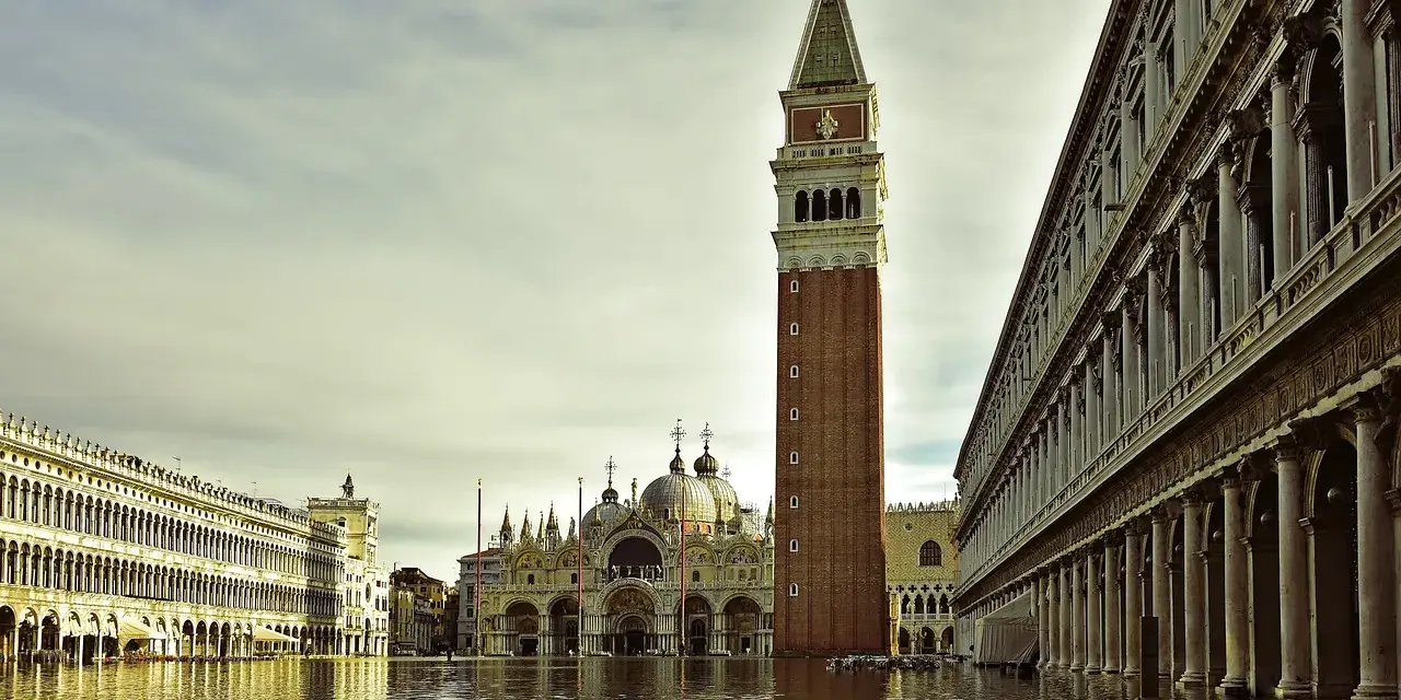 La maestosa torre di Piazza San Marco si erge sull'acqua alta, riflettendosi nel canale che lambisce i palazzi storici.
