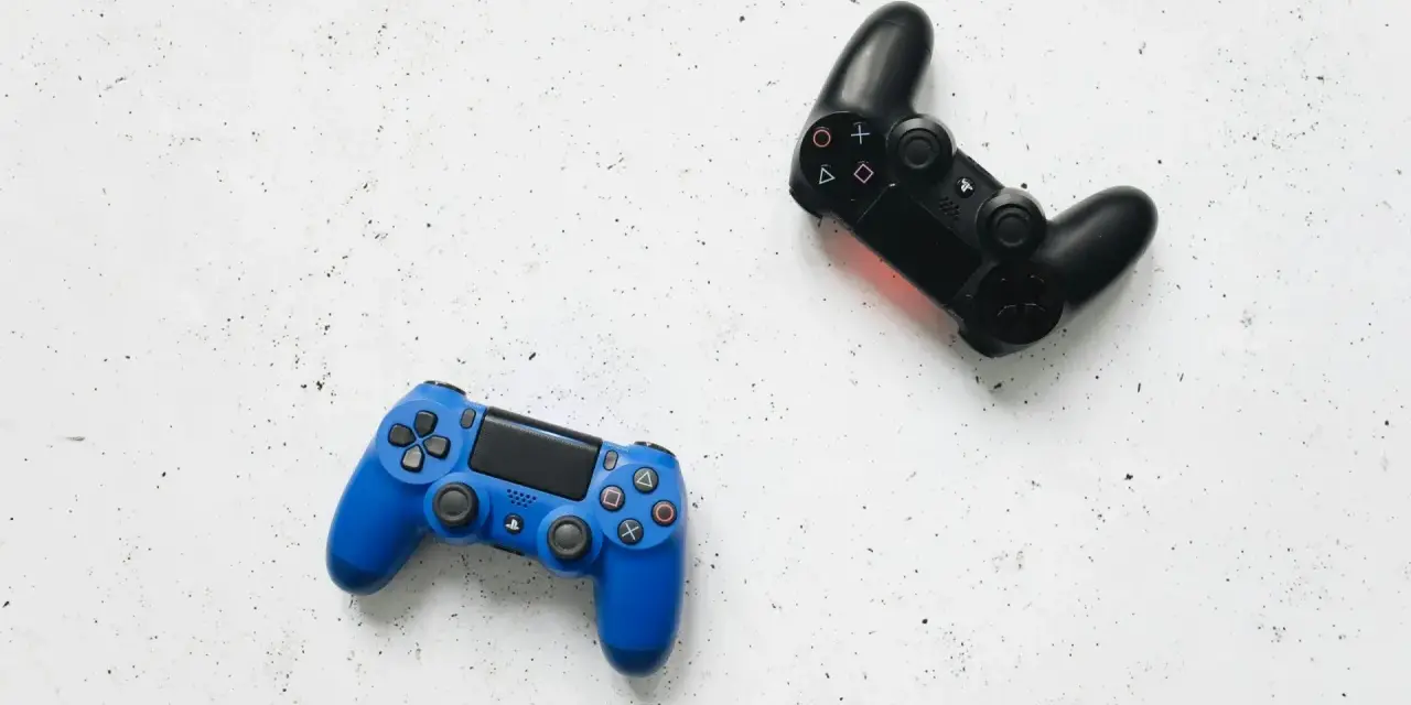 Dos mandos de videojuego, uno azul y otro negro, listos para una intensa sesión de videojuego de acción y aventura.