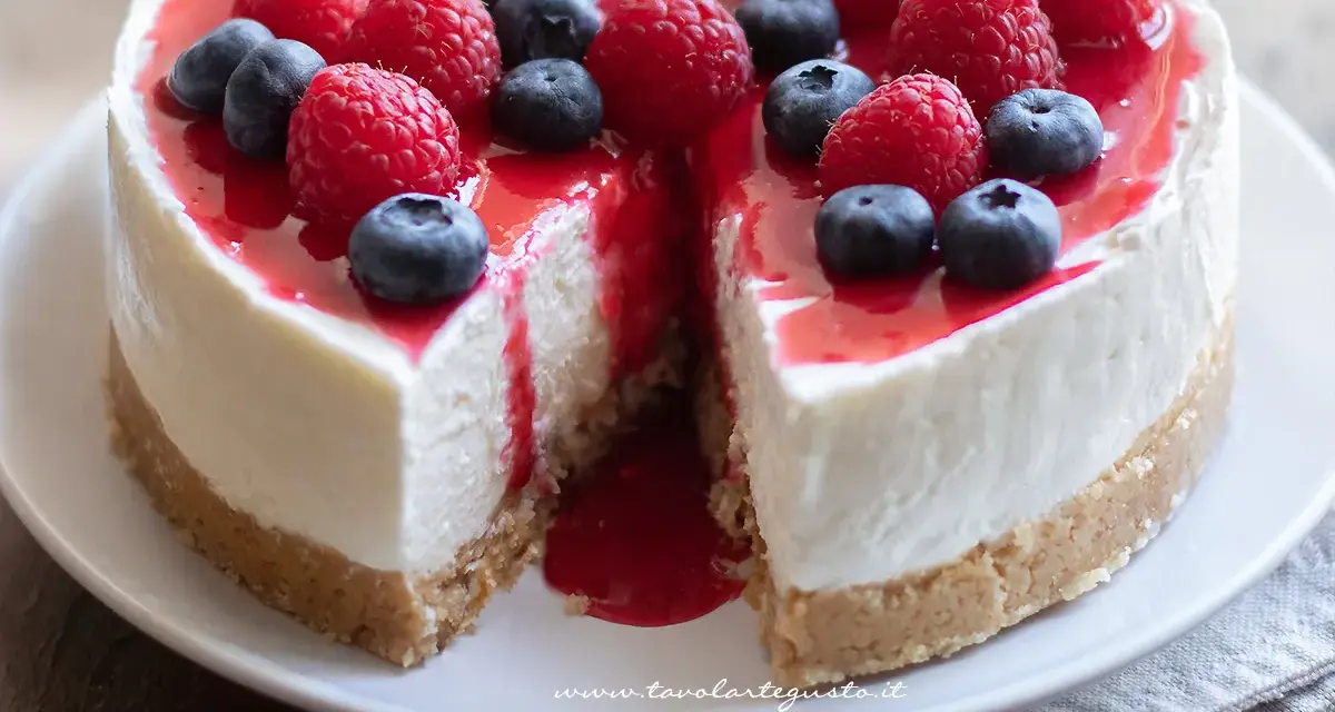 Delizioso cheesecake con mascarpone, guarnito con lamponi freschi, mirtilli e una cascata di salsa rossa.
