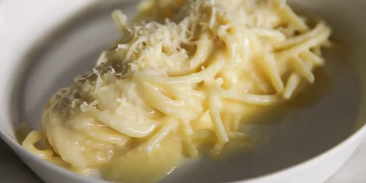 Un piatto di pasta burro e parmigiano, cremoso e invitante, con una spolverata di formaggio grattugiato.