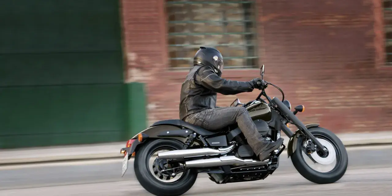 Motocyklista na Honda Shadow 750, z uwzględnieniem danych technicznych, pędzi ulicą.
