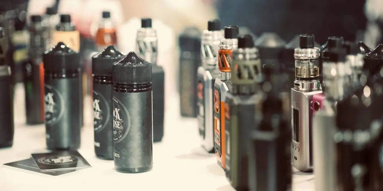 Botellas de líquidos para vapear, con diversos potenciadores de sabor, y dispositivos electrónicos en exhibición.