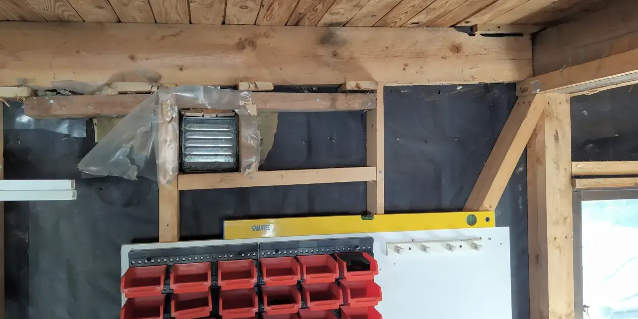 Pågår arbete för att isolera garage. Syns träbjälkar, isolering och förvaringssystem med fack.