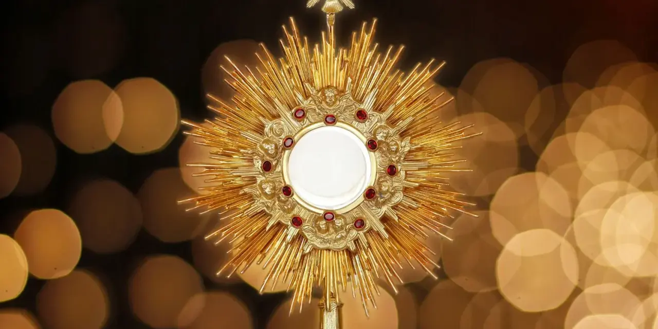 Złota monstrancja z hostią, otoczona promieniami i rubinami, symbolizuje pierwsze piątki miesiąca.