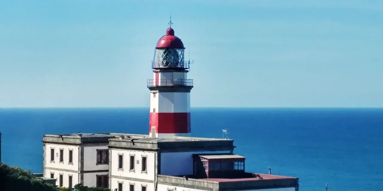 Faro blanco y rojo en la costa, un punto de referencia en la ruta de Vigo a Baiona.