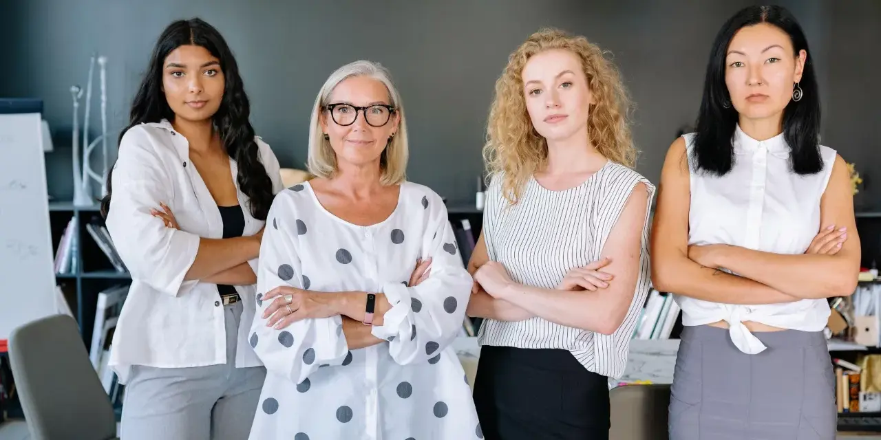Cuatro mujeres emprendedoras, diversas en edad y etnia, posan con confianza en una oficina.