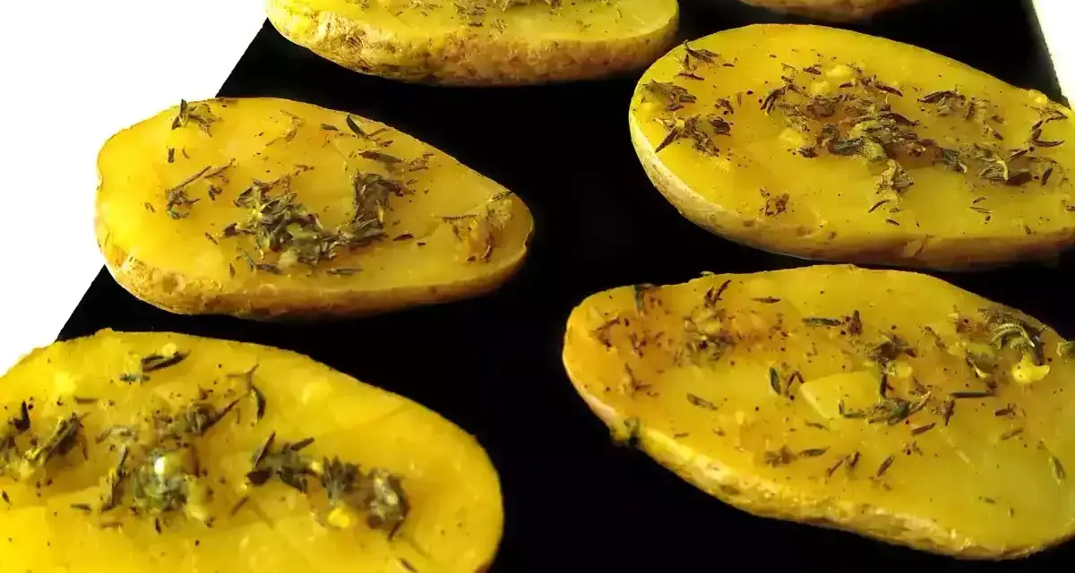 Patatas al microondas cortadas por la mitad, sazonadas con hierbas y especias, listas para cocinar.