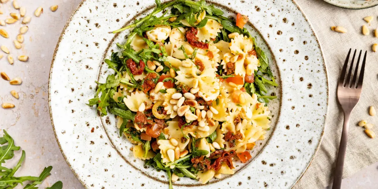 Mediterraner Salat mit Farfalle, getrockneten Tomaten, Rucola, Pinienkernen und Mozzarella.
