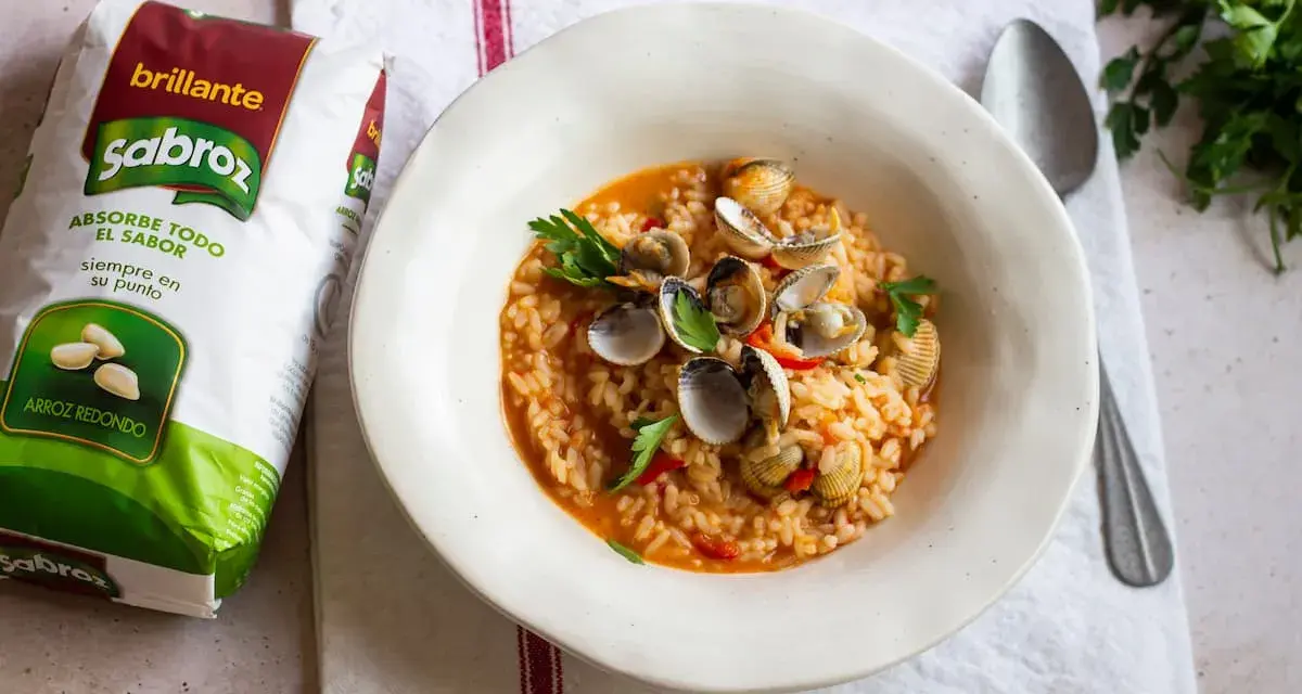 Delicioso arroz con berberechos, preparado con arroz redondo Sabroz, adornado con perejil fresco.