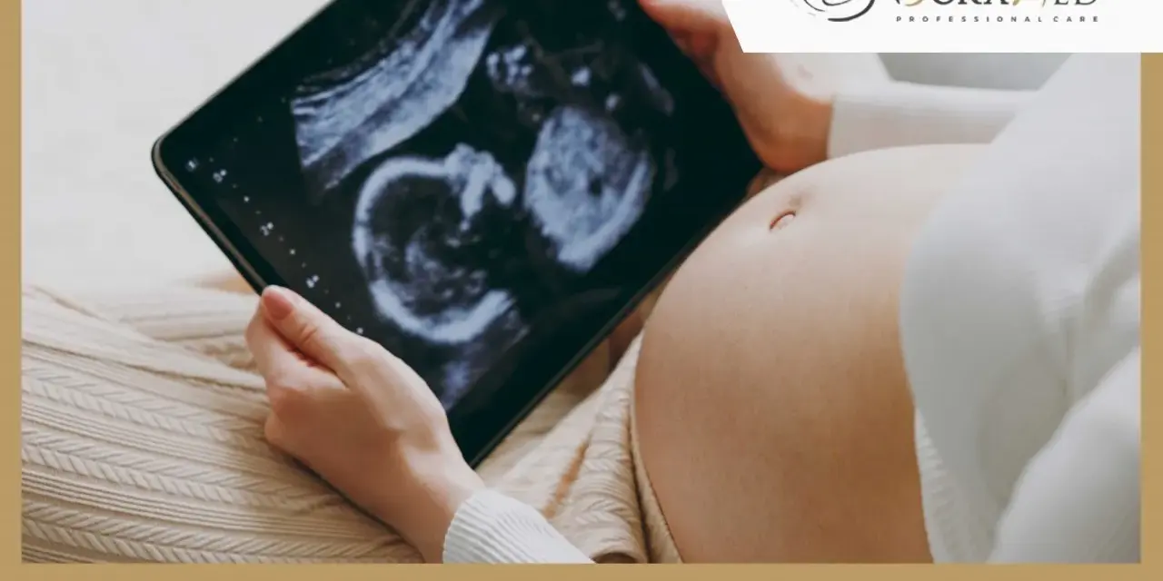 Kobieta trzyma tablet z obrazem USG płodu na tle ciążowego brzucha.