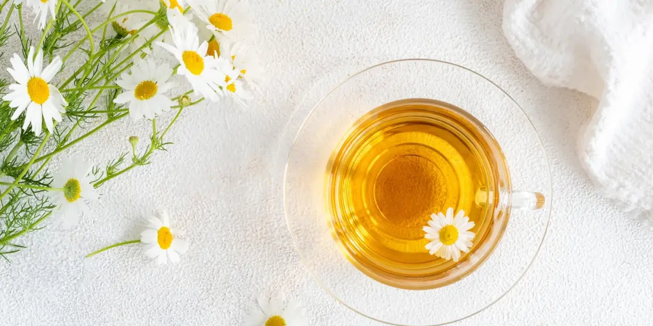 Un mazzolino di margherite e una tazza di tisana dorata. Nonostante la sua apparenza innocua, la camomilla fa male al cuore se consumata in eccesso.
