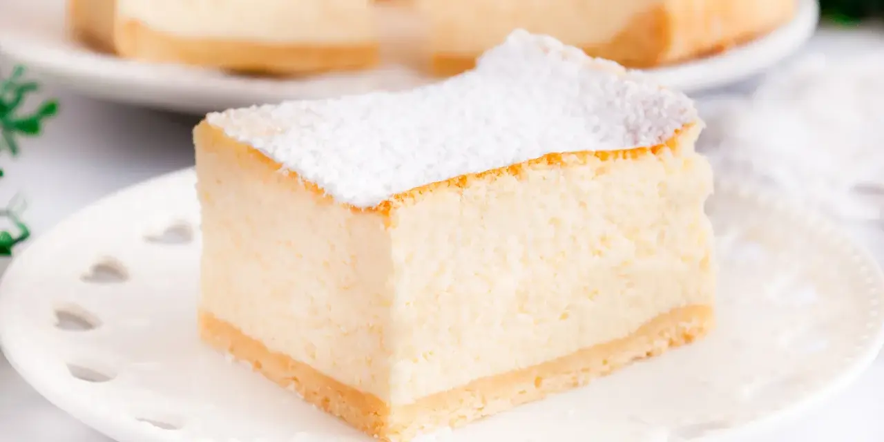 Puszysty sernik z mascarpone, oprószony cukrem pudrem, na białym talerzyku. Idealny na deser.