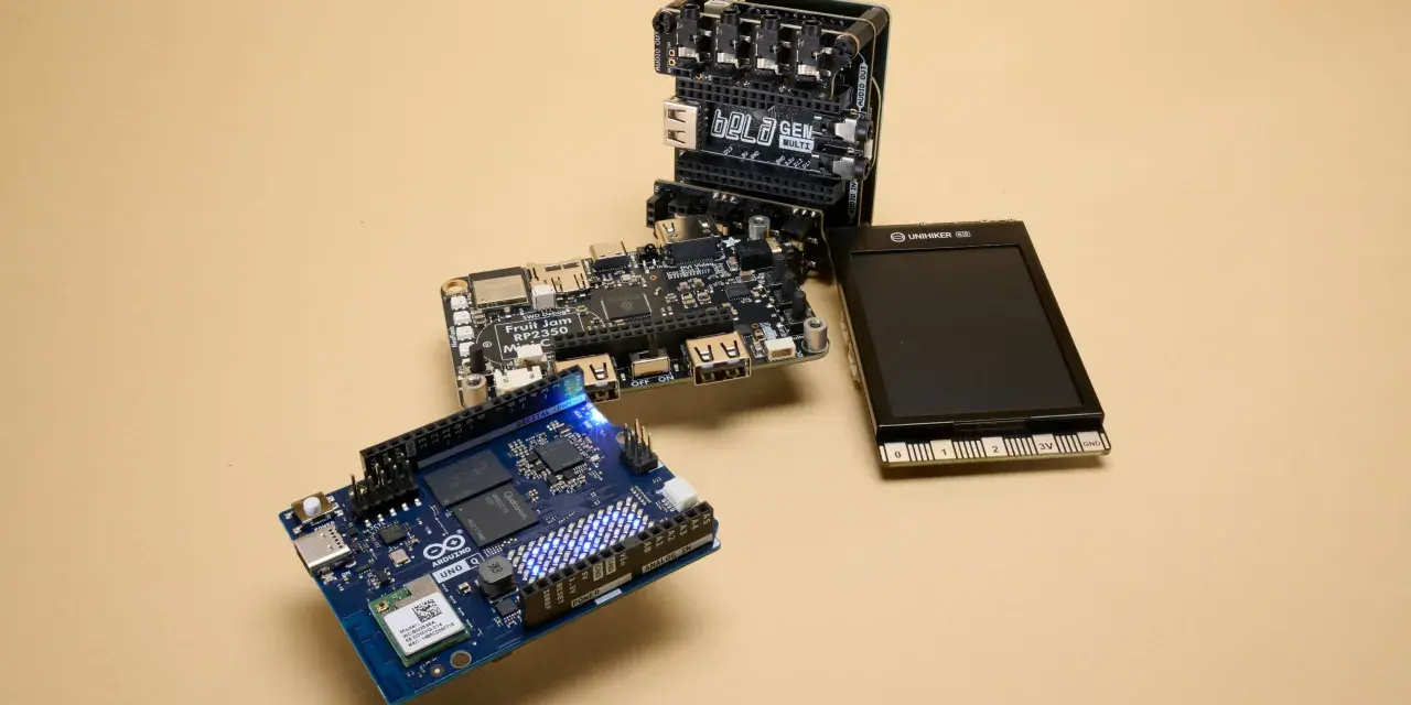 An Arduino Uno, a Bela GEN MULTI, and a Fruit Jam RP2350 board are arranged on a beige surface, showcasing some of the best microcontroller options for makers.