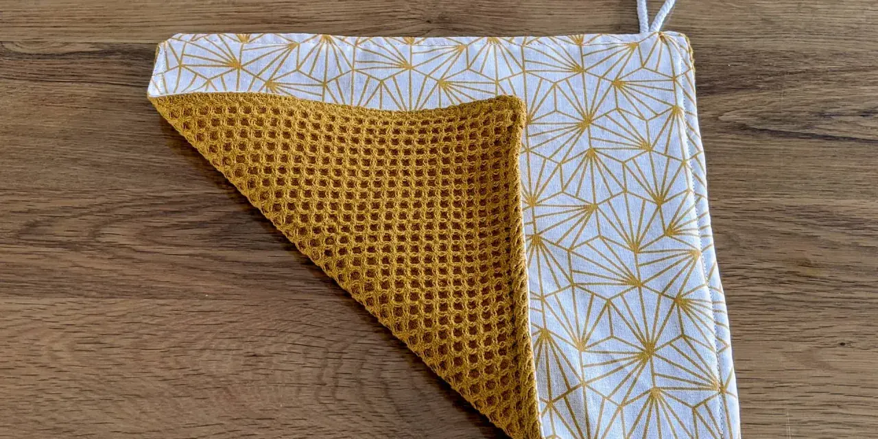 Tuto essuie-tout lavable sans pression : un tissu blanc à motifs géométriques dorés et un tissu éponge moutarde.