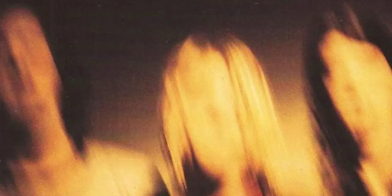 Rozmyte postacie, jakby w ruchu, na tle sugerującym okładkę albumu "Smells Like Teen Spirit" Nirvany.