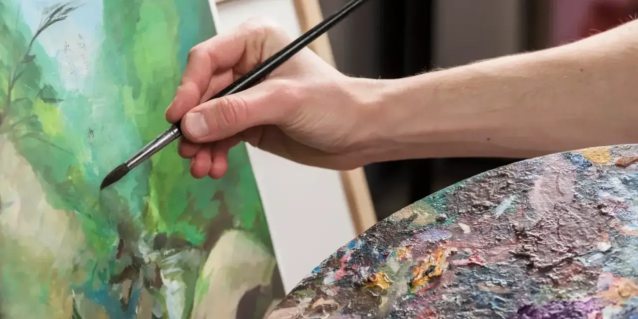 Main d'artiste peignant une scène verdoyante avec une peinture à l'acrylique. Palette de couleurs vibrantes.