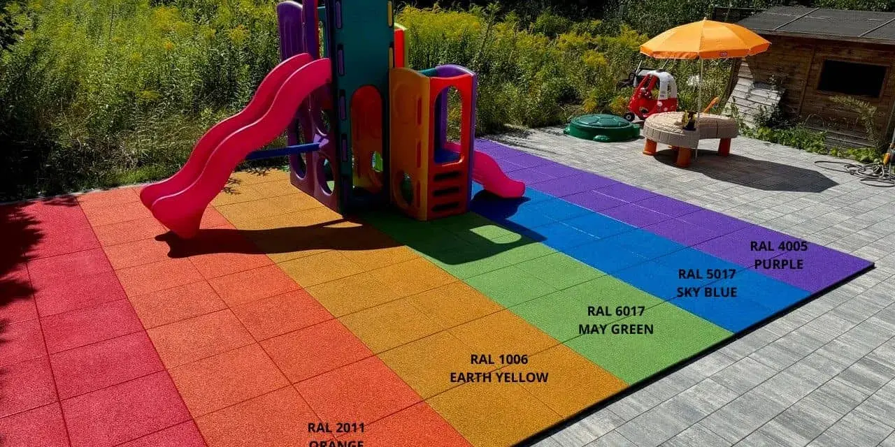 Kolorowy plac zabaw z tęczową nawierzchnią gumową i zjeżdżalnią.