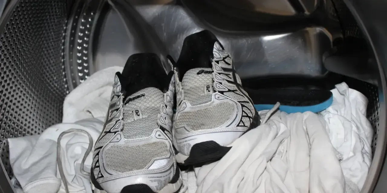 Scarpe da ginnastica pronte per essere lavate in lavatrice, insieme ad alcuni asciugamani bianchi.