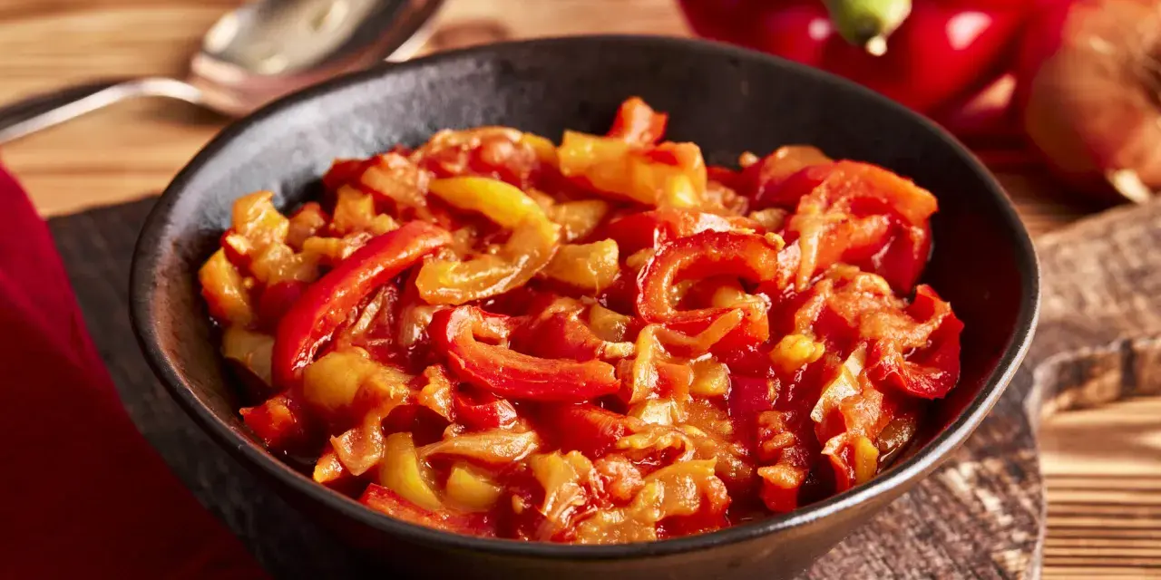 Schmor paprika mit Zwiebeln, ein Gericht, das man gut letscho selber machen kann. Serviert in einer Schüssel auf einem Holztisch.